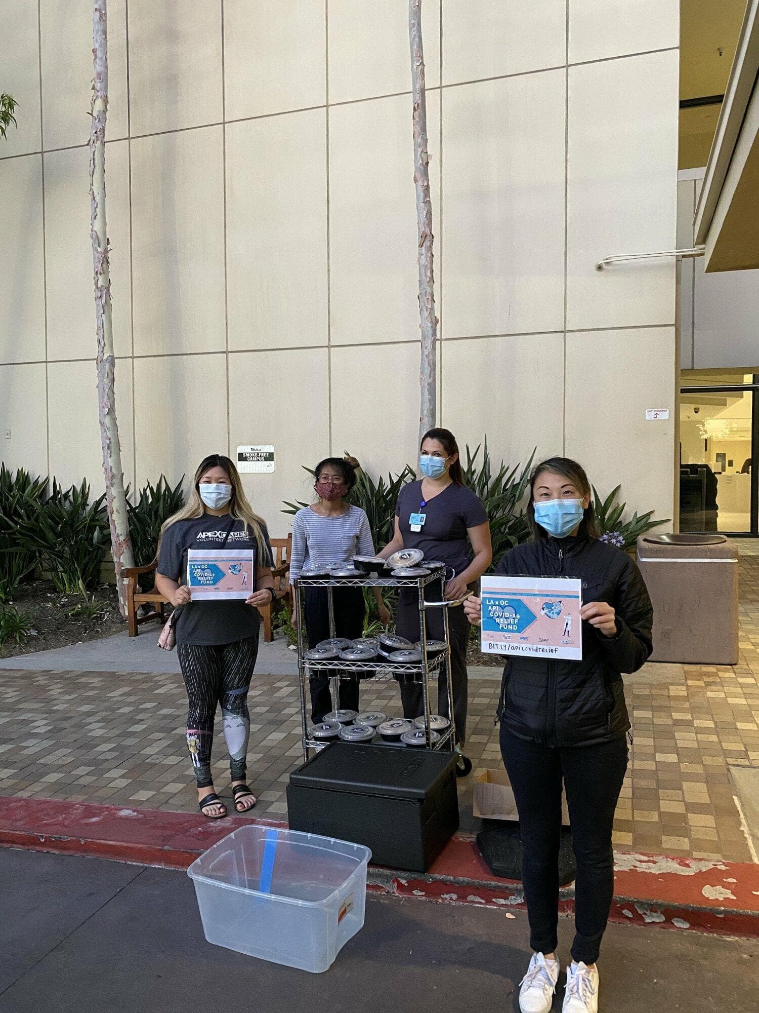 Masked volunteers delivering boxed meals to healthcare workers outside a hospital