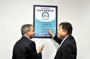 Covered California Executive Director Peter Lee and KCAL President Kenny Chang look over a Covered California key dates poster